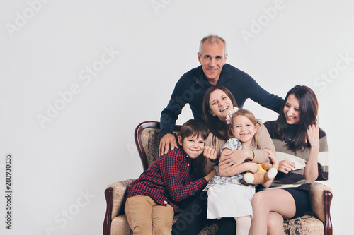 concept of happy childhood, family, love - group of people on a white background: adults and children with toys sitting on the same couch