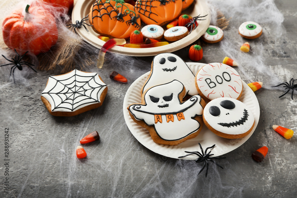 Halloween gingerbread cookies with candies on grey background