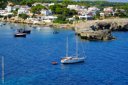 View on white boats, the beach and village Alcaufar on Menorca.