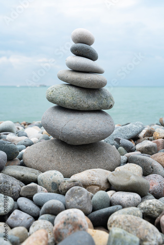 Stack of white pebbles stone against blue sea background for spa  balance  meditation and zen theme.