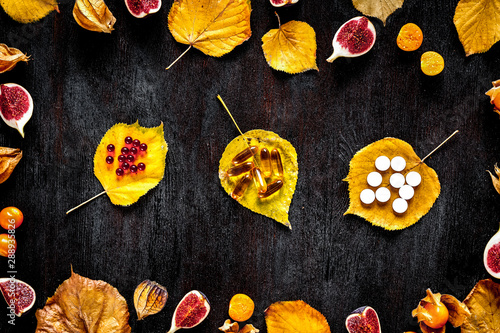 autumn leaves and sliced fruit on wooden background top view