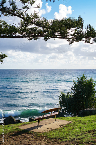 Lonely bench on the shore of the ocean with a stunning view of crashing waves against the coast.