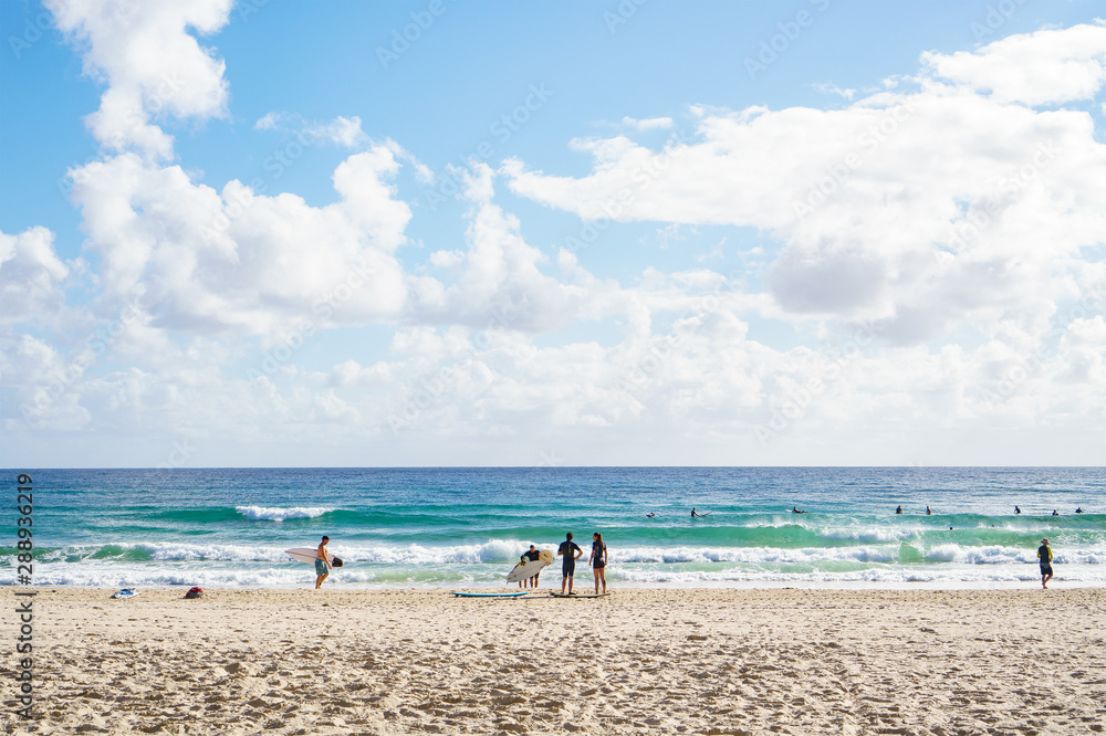 Stunning view of tropical sandy beach, full of surfers and beach goers enjoying relaxing lifestyle on the Gold Coast, Australia.