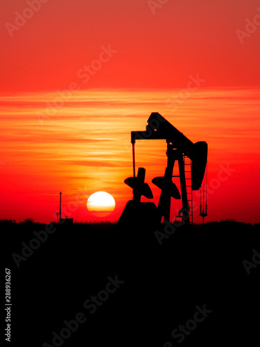 Pumpjack in oilfield at sunrise.