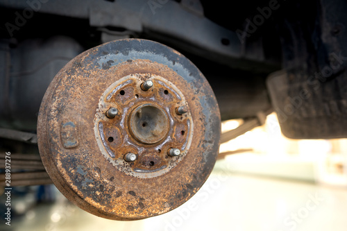 Close up of old Brake Disc of the vehicle for repair.Automobile mechanic in process of new tire replacement.Car brake repairing in garage.Car Service and technician concept.