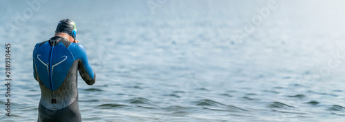 Obraz na plátně Panorama of a triathlete in a wetsuit getting ready to swim right before a triat
