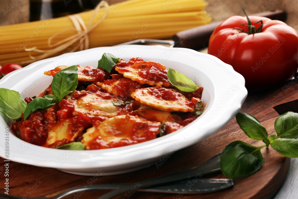 Ravioli with tomato sauce garnished with parmesan cheese and basil on rustic table Ravioli with tomato sauce garnished with parmesan cheese and basil on rustic table