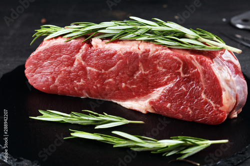 Steak raw. Barbecue Rib Eye Steak or rump steak on dark rustic table photo