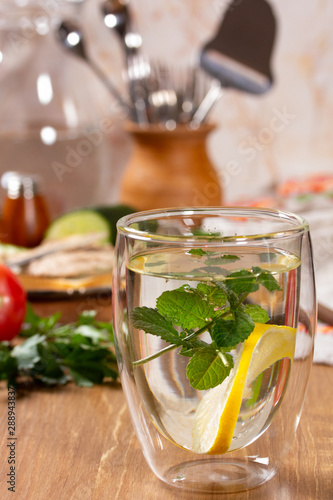 Refreshing drink with lemon and mint in a glass cup