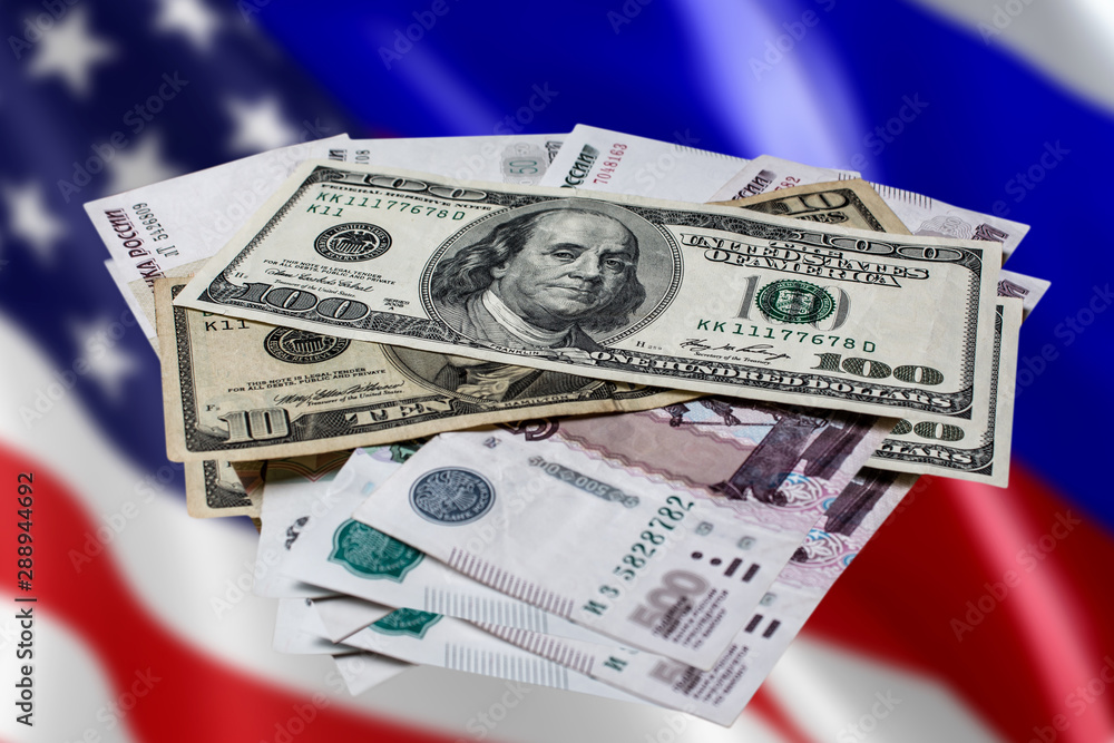 Us dollars and Russian rubles on an abstract background. The Russian ruble against the us dollar against the flags of America and Russia. Us dollars and Russian rubles on an abstract background. The Russian ruble against the us dollar against the flags of America and Russia.