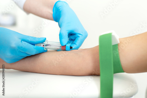 a nurse in the clinic inserts a catheter into a vein for blood testing for a young girl