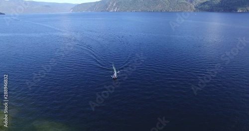 Aerial view of Teletskoye lake and yellow boat in motion. The Republic of Altai, Russia