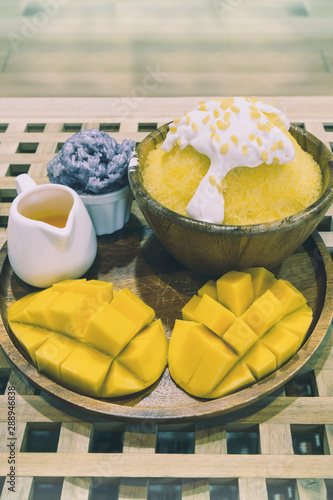 Fototapeta Naklejka Na Ścianę i Meble -  Bingsu or shaved ice dessert topped with coconut fresh cream and mango sliced served with sticky rice and mango sauce, sweet dessert in Korean style.