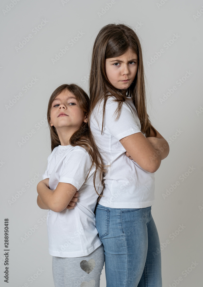 portrait of sisters standing back to back not talking to each other