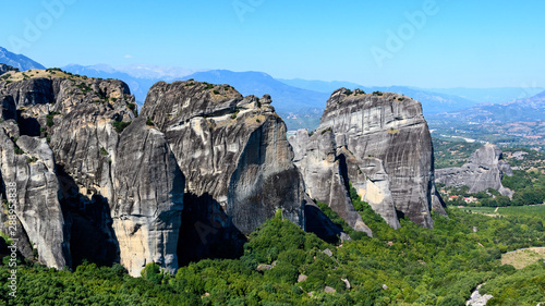 Rock formations of Meteora mountains in Greece with blue sky and green forest