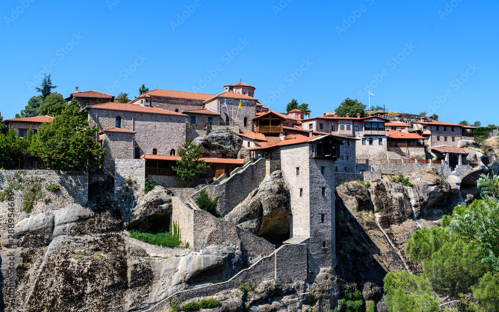 Rock formations of Meteora mountains and the monastery in Greece with blue sky and green forest