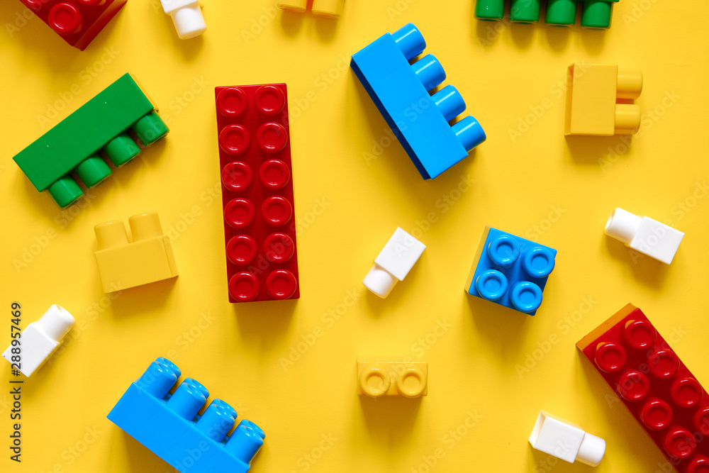 Colorful plastic building blocks flat lay. Yellow background. Child developing game. Pattern Colorful plastic building blocks flat lay. Yellow background. Child developing game. Pattern