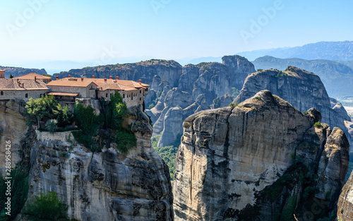 Rock formations of Meteora mountains and the monastery in Greece with blue sky and green forest
