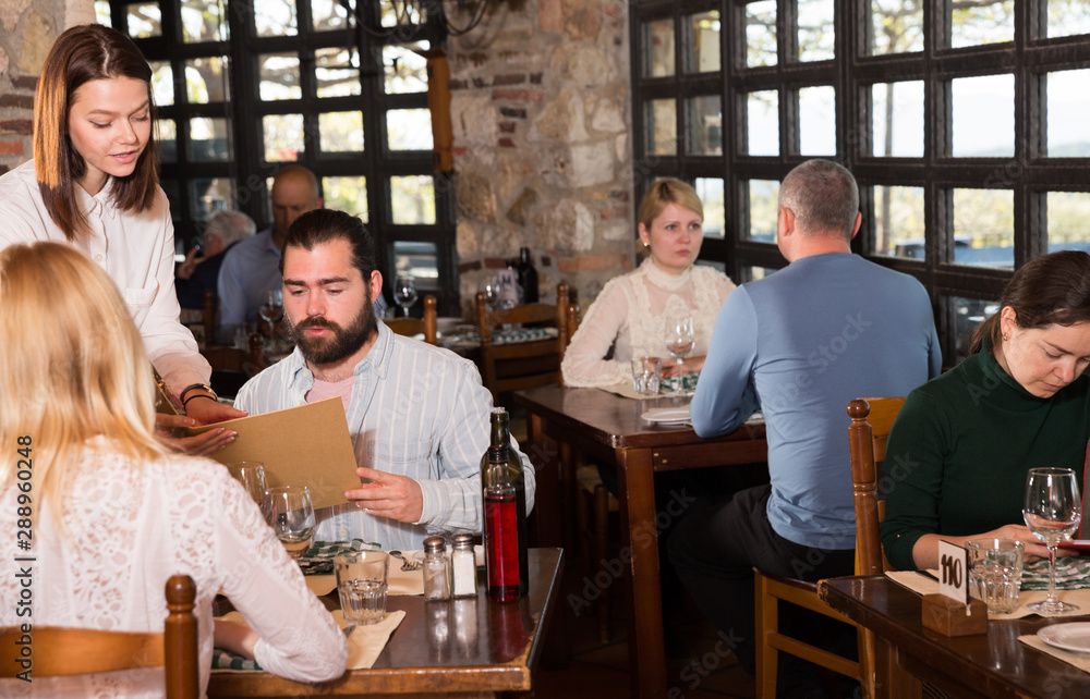 Guests of the country restaurant discuss menu with waitress