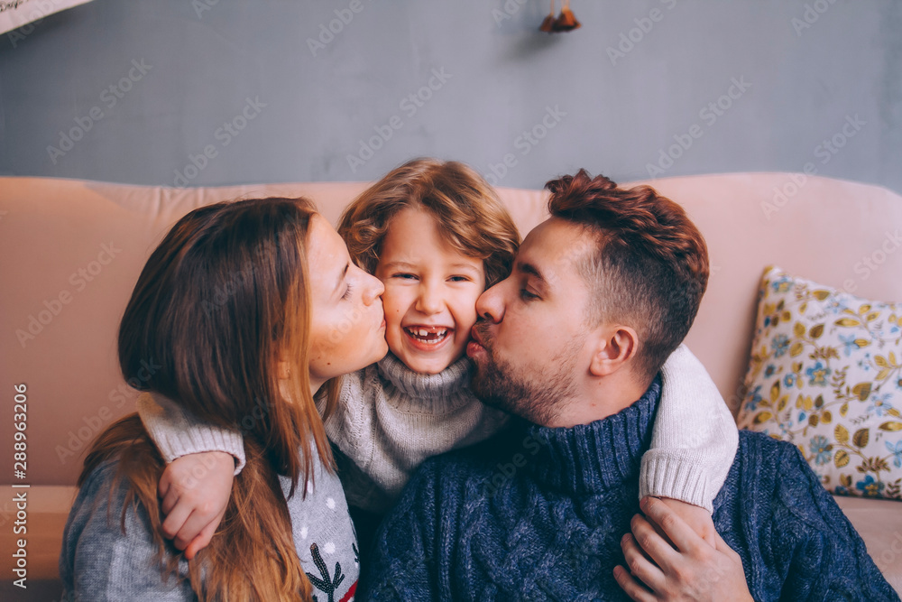 Foto de Dad and mom kiss his son on the cheeks. Happy boy smiles a ...