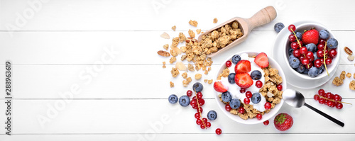 Breakfast with yogurt, muesli and berries on white wood background, top view, space for text. photo