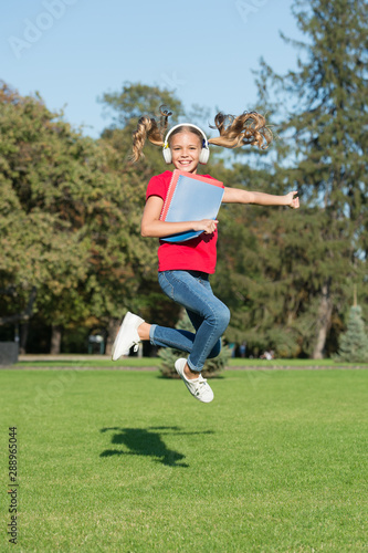 Happy studying. Girl listening music modern gadget. Kid happy wireless headset running with school books. Stereo headphones. Kid using modern technology. Modern schoolgirl. Joy of learning. Have fun