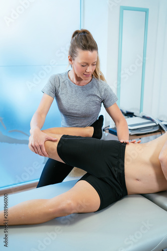 Concept of muscle health and relaxation. A woman physiotherapist stretches a client's leg while lying down.