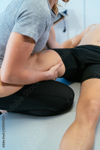 Photo detail of a physiotherapist woman massaging the leg and quadriceps to a man client lying down. Concept of muscle health and relaxation.