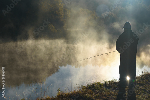 man catches fish on the river Snov in autumn, October 2018. Ukraine, the city of Chernigov photo