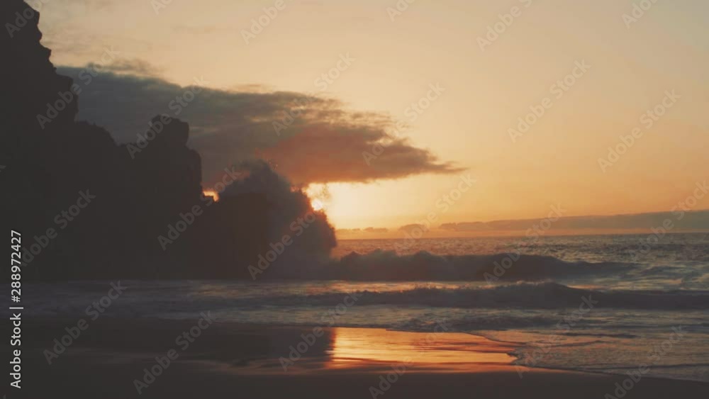 Seascape at sunset. Waves crash against a rock with the setting sun. Slowmotion Seascape at sunset. Waves crash against a rock with the setting sun. Slowmotion