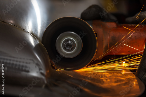 Worker cutting metal part using hand Angle Grinder Machine. Freeze motion sparks , close-up.