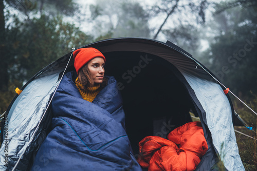 tourist traveler ralaxing in camp tent in foggy rain forest, hiker woman enjoy mist nature trip, green trekking tourism, rest vacation concept camping holiday, campsite rest photo