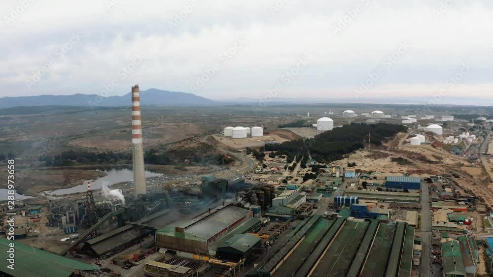 Industrial zone with a large red and white pipe next to the ocean. Pollution of the environment: climate change. Aerial view in 4K UHD Industrial zone with a large red and white pipe next to the ocean. Pollution of the environment: climate change. Aerial view in 4K UHD