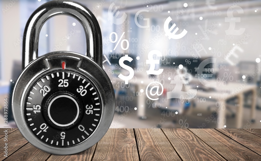 Combination lock on a wooden table with an illustration of Finance Combination lock on a wooden table with an illustration of Finance