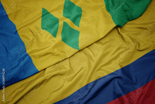 waving colorful flag of colombia and national flag of saint vincent and the grenadines.