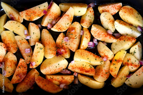 Cut potatoes seasoned with purple onion, basil and smoked paprika. Top view.