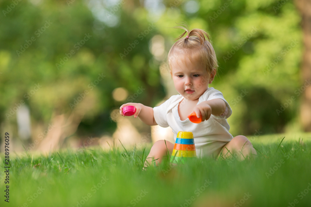 baby girl in a white sandpit on the green grass playing pyramid baby girl in a white sandpit on the green grass playing pyramid