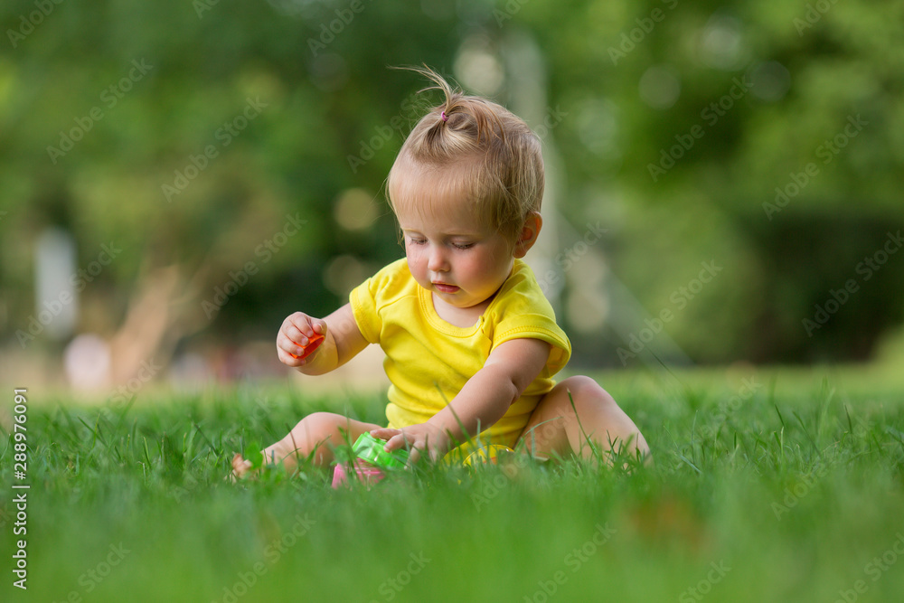 baby girl in a white sandpit on the green grass playing pyramid
