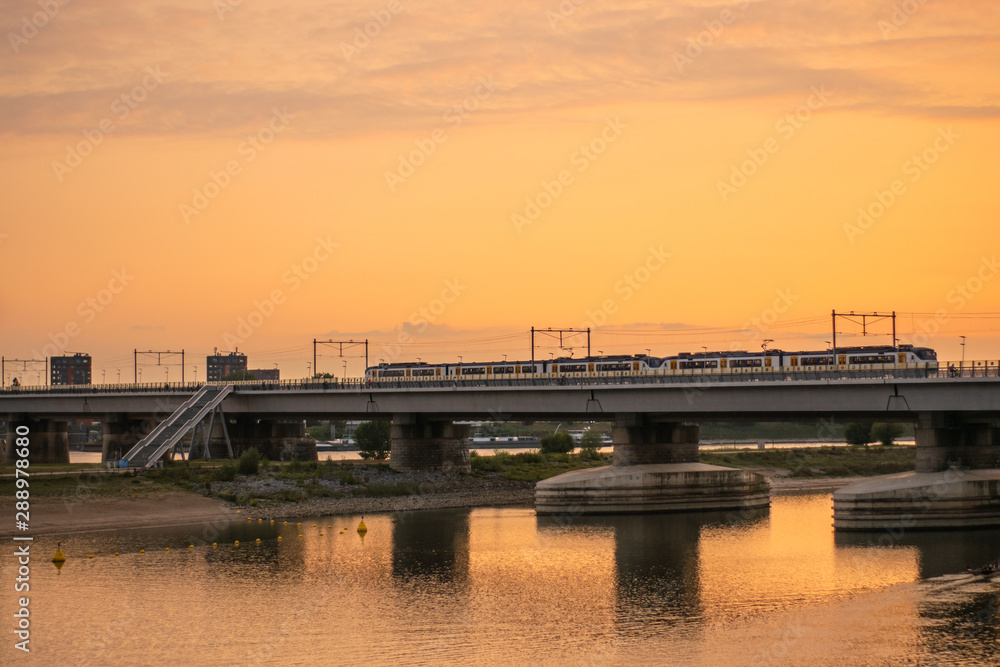 Dutch train crossing bridge at sunset