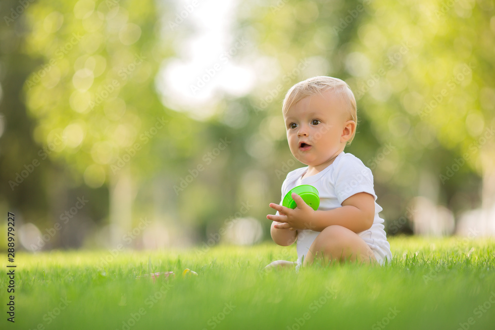baby in a white bodysuit sitting on the green grass playing baby in a white bodysuit sitting on the green grass playing