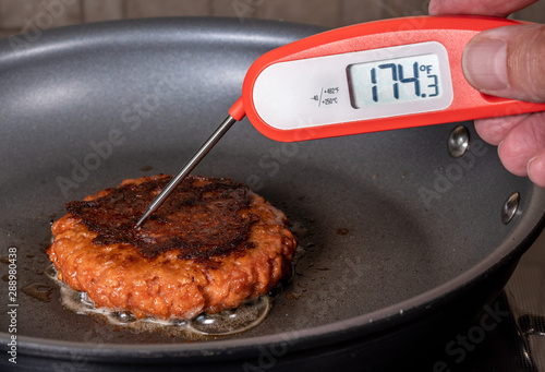 Fotografía Charred and ready to eat plant-based burger in frying pan with instant thermomet