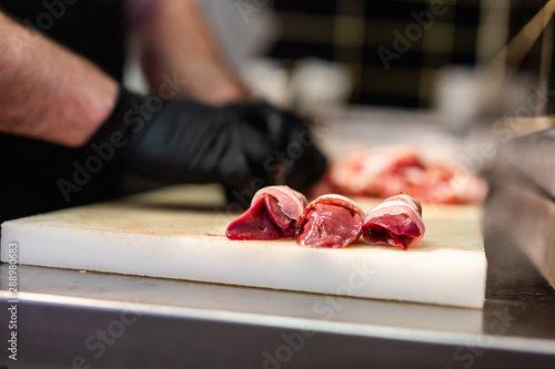 Close up on butcher's hands in gloves working in butchery.