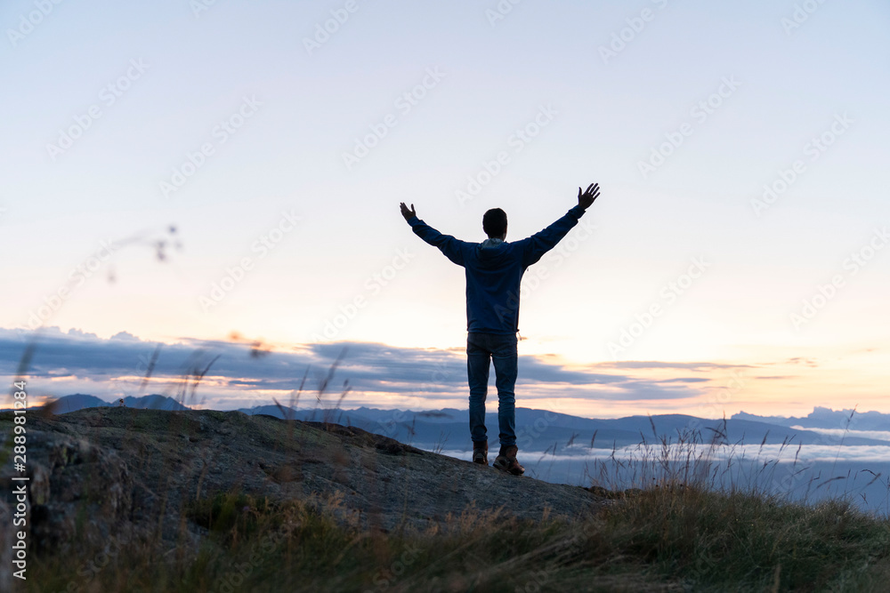 hiker celebrating success on top of a mountain above the clouds. Young man enjoying freedome, Mountaineering sport lifestyle concept hiker celebrating success on top of a mountain above the clouds. Young man enjoying freedome, Mountaineering sport lifestyle concept