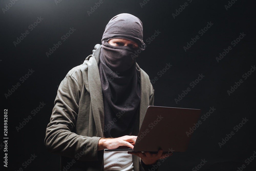 A terrorist with a laptop is preparing a crime at night A terrorist with a laptop is preparing a crime at night