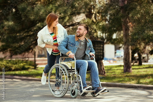 Young man in wheelchair and joyful woman at park