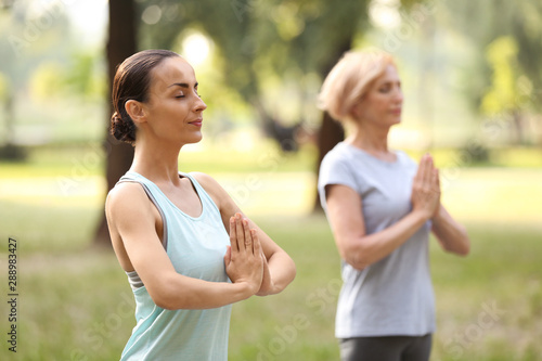 Women practicing yoga in park at morning