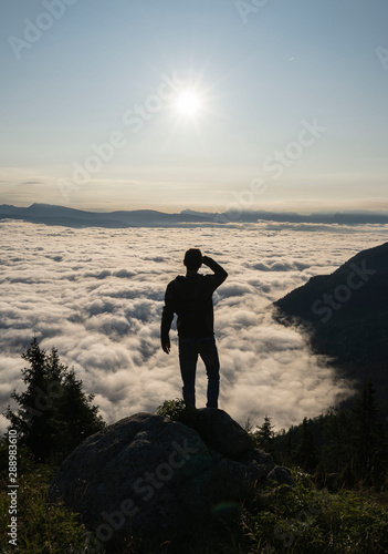 hiker standing on the top of a mountain and enjoying an amazing view over a cloud covered valley. Luck happiness and freedom concept in South Tyrol Italy