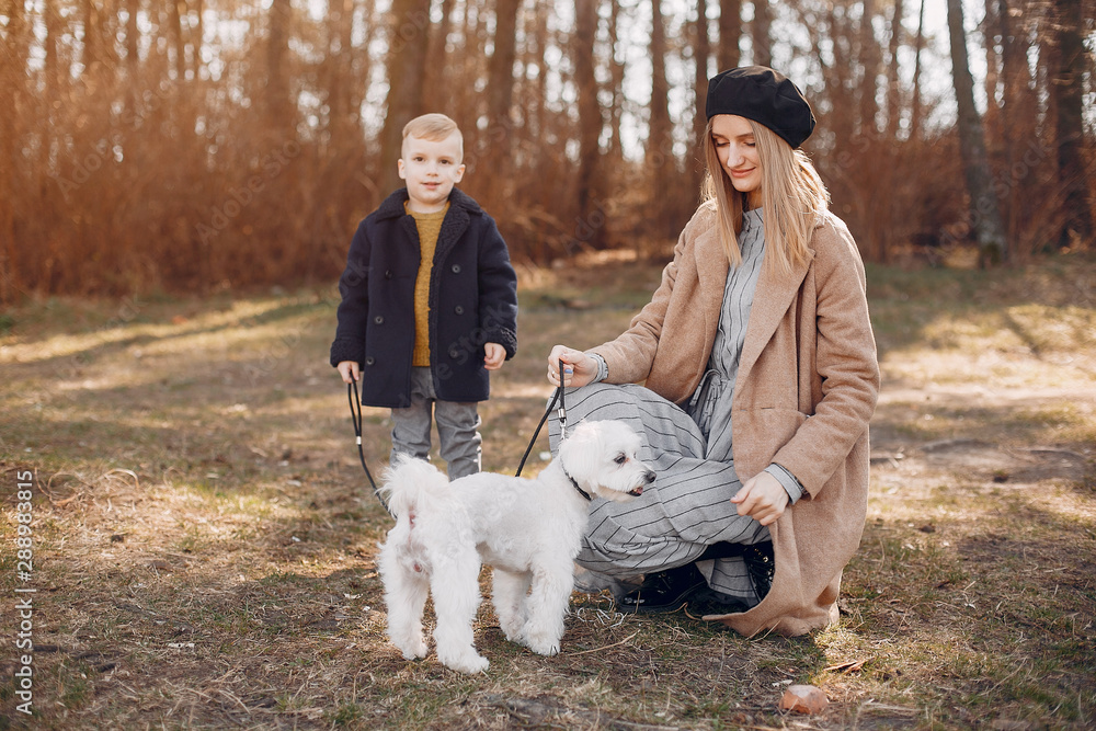 Family in a summer park. Mother in a brown coat. Cute little boy with a dog Family in a summer park. Mother in a brown coat. Cute little boy with a dog