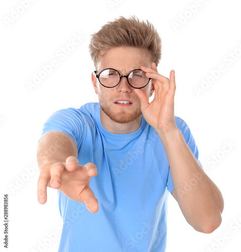 Young man with vision problem wearing glasses on white background