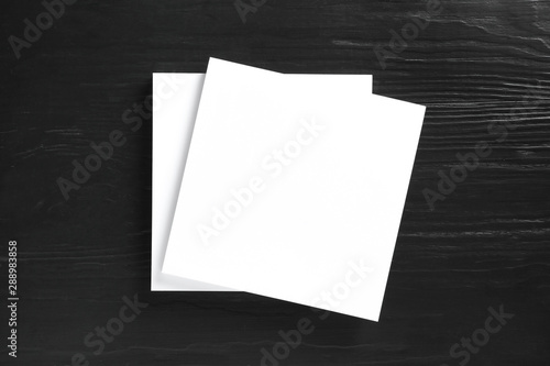 Stack of blank paper sheets for brochure on black wooden background, top view. Mock up © New Africa